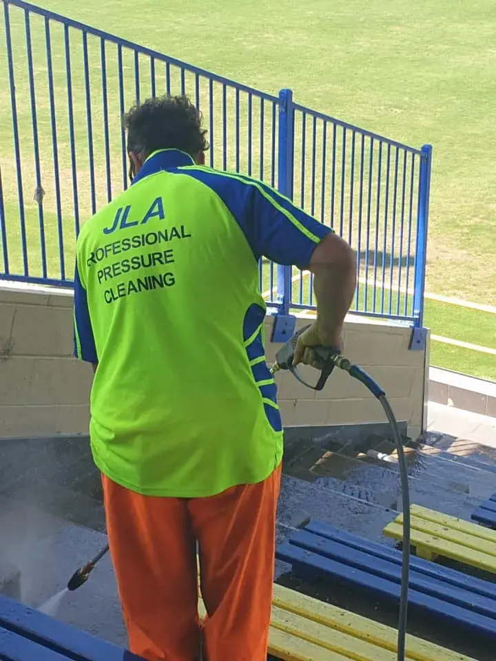 Technician pressure washing an elevated grandstand railing